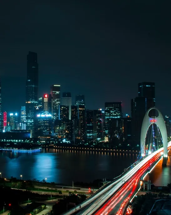 Cidade à noite, com os prédios iluminados e o trânsito numa ponte